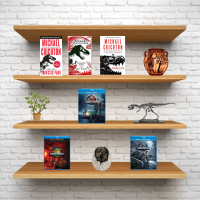 A white brick wall with wooden shelves. An assortment of books, movies and knick knacks are on the shelves.