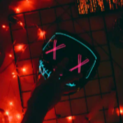 A glowing mask with neon X eyes on a table, lit by red string lights, with a hand reaching toward it.
